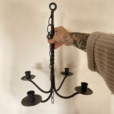 a person is holding a candle holder in the shape of a chandelier