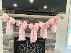 a fireplace decorated with pink tissue pom poms and a flat screen tv above it