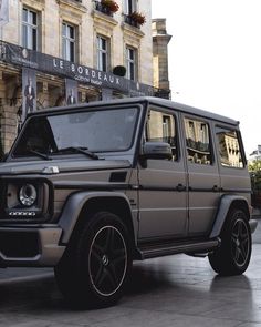 a mercedes benz g class parked in front of a building