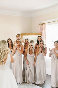 a group of bridesmaids standing in front of a mirror with their arms around each other