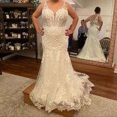 a woman standing in front of a mirror wearing a wedding dress