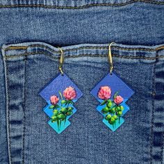 two pink roses are hanging from the back pocket of a pair of blue jean pants