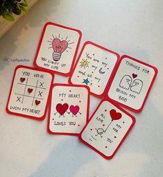 four red and white coasters with handwritten words on them sitting on a table