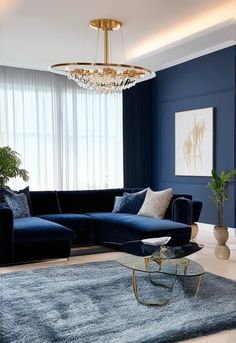 Create a luxurious modern living room with a sophisticated blue color scheme. The space should feature a plush, deep blue velvet sectional sofa paired with sleek metallic gold side tables. A soft, textured area rug in shades of light blue and gray anchors the space. Add a striking modern chandelier with crystal accents, and position floor-to-ceiling windows that allow natural light to flood Gold Side Table, Velvet Sectional, Shades Of Light Blue, Blue Color Schemes