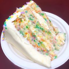 a slice of cake with white frosting and sprinkles on a plate