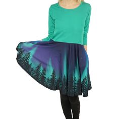 Introducing our enchanting Northern Lights Skirt – a mesmerizing masterpiece that captures the ethereal beauty of the Arctic skies. Crafted with care, this skirt features a stunning design inspired by the dancing hues of the Aurora Borealis. Its deep midnight blue fabric serves as the perfect canvas for the vibrant emerald greens, electric purples, and shimmering pinks that mirror the celestial spectacle. This skirt combines style and comfort effortlessly, making it an ideal choice for both casual outings and special occasions. Embrace the magic of the Northern Lights and light up your wardrobe with this captivating dress. Product Specifications Kids 3/4th-sleeve twirl dress with pockets Cotton knitted top and polyester knitted skirt Color: Green top with blue, purple, green, and black nor Northern Lights Design, The Aurora Borealis, Knitted Skirt, Light Dress, Twirl Dress, The Aurora, Knitted Top, Green Top, Ethereal Beauty