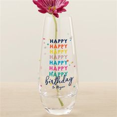 a pink flower in a clear vase with happy birthday messages on it's side