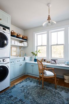 a laundry room with washer and dryer next to each other in front of two windows