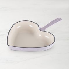 a heart shaped dish with a spoon in it on a white counter top next to a marble surface