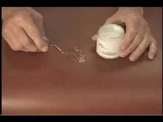 a person is holding a spoon over a jar on a table with the lid open