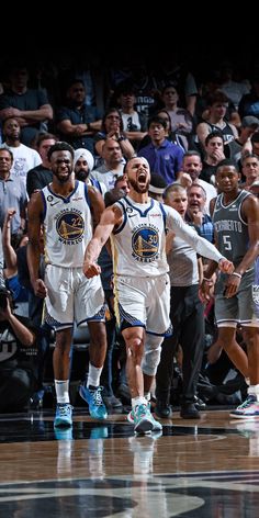 two basketball players are walking on the court with their arms in the air as people watch