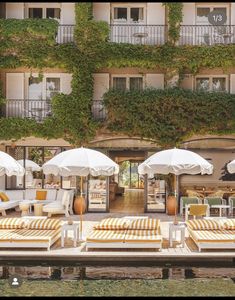 lounge chairs and umbrellas are lined up by the pool in front of an apartment building