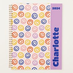 a spiral notebook with colorful smiley faces and the words charlotte on it, in front of a white background