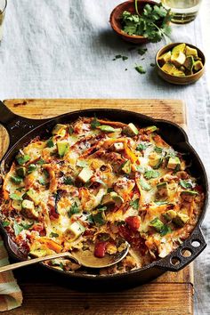 a casserole dish with vegetables and meat in it on a wooden cutting board