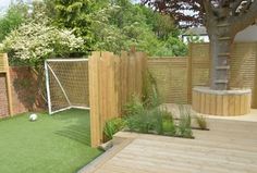 a backyard with a soccer goal and wooden fenced in area next to a tree