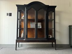 a black china cabinet with glass doors and shelves