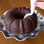 a bundt cake is being frosted with icing on a platter,