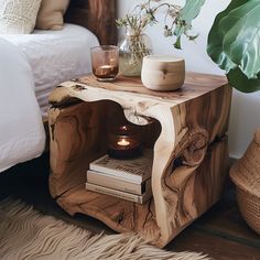 a wooden table with a candle on it next to a potted plant and a bed