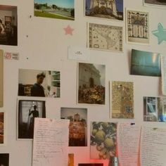 a refrigerator covered in pictures and magnets next to a wall with writing on it