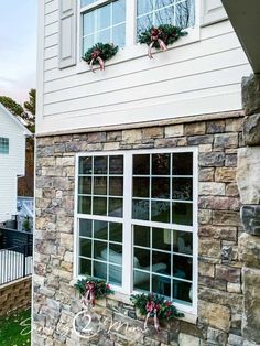 a brick building with two windows and wreaths on the window sill in front of it