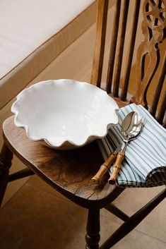 a white bowl sitting on top of a wooden table next to a knife and fork