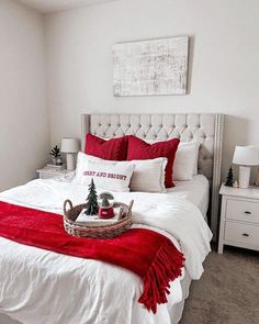 a white bed with red pillows and blankets