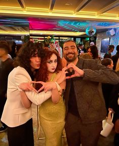 two women and a man posing for the camera in front of a group of people