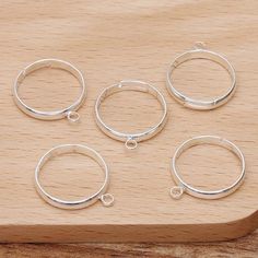 four silver rings sitting on top of a wooden board