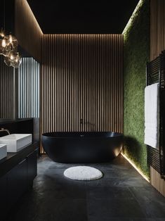 a black bath tub sitting in a bathroom next to a white sink and two sinks