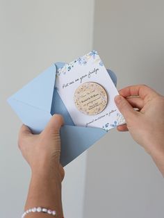 a woman is holding an envelope with a card inside it, and another hand holds the envelope