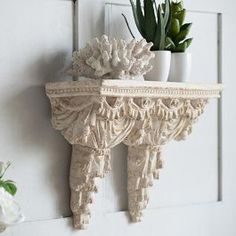 a white shelf with two potted plants on it