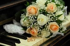 a bouquet of white and peach roses sitting on top of an old piano keyboard with baby's breath