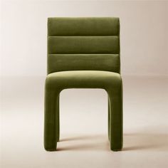 a green chair sitting on top of a white floor next to a wall with a light colored background