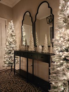 a white christmas tree sitting in front of a mirror on top of a wooden table