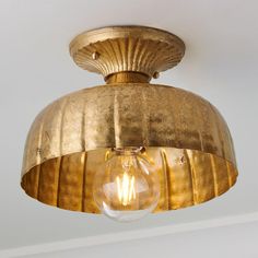 a gold colored light fixture with a clear glass bulb hanging from it's ceiling