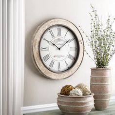 a clock on the wall next to a potted plant and vase with flowers in it