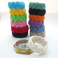 a stack of multicolored bracelets next to a pocket watch on a white surface