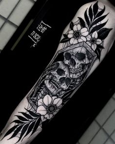 a man's arm with a skull and flowers on it