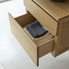 an open drawer in a wooden cabinet with a bowl on the counter and towel folded inside