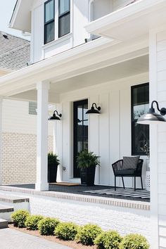 the front porch of a white house with black shutters