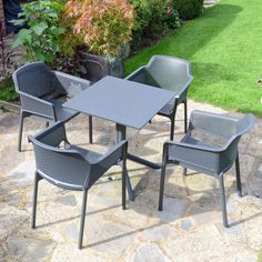 an outdoor table and chairs set up on a stone patio with grass in the background