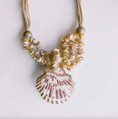 a necklace with seashells and beads hanging from it's sides on a white surface