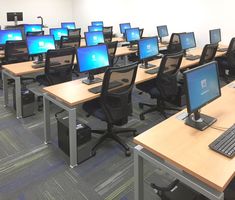 rows of desks with computers on them in an office