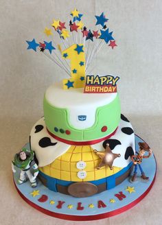 a birthday cake with toy figures on top and stars in the sky decorationating it