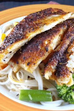 the meal is prepared and ready to be eaten on the plate, including chicken, noodles, broccoli, and carrots