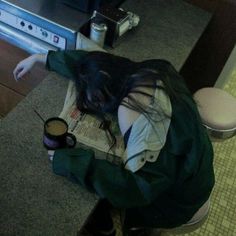 a woman is sitting on the floor with her head down and holding a coffee cup