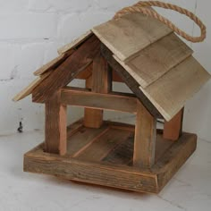 a birdhouse made out of wood with a rope hanging from the top and bottom