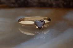 a heart shaped diamond ring sitting on top of a table