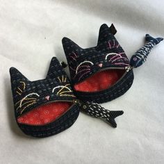 two black cat purses sitting on top of a white sheet