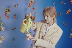 a person in a suit and tie holding a yellow vase with flowers coming out of it